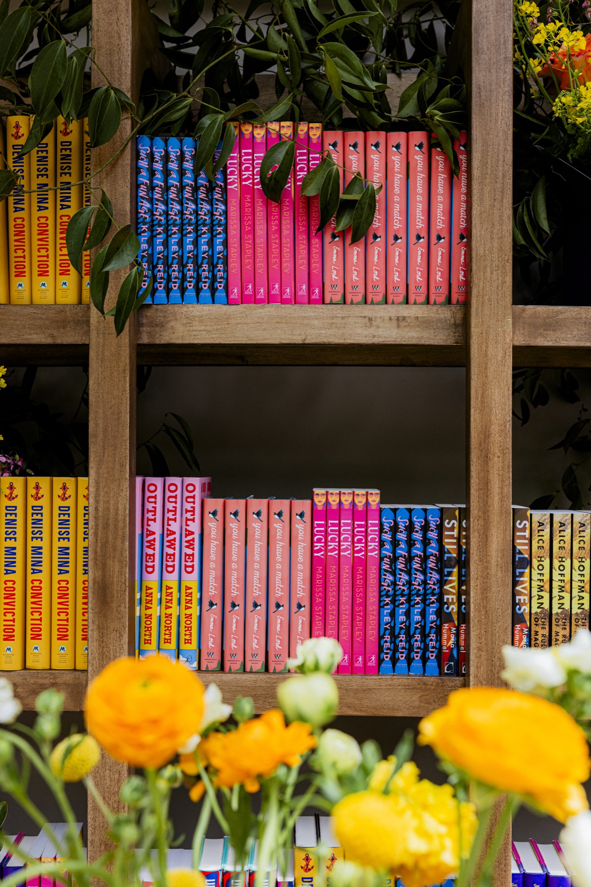 Colorful books displayed among flowers and greenery at a Reese’s Book Club activation