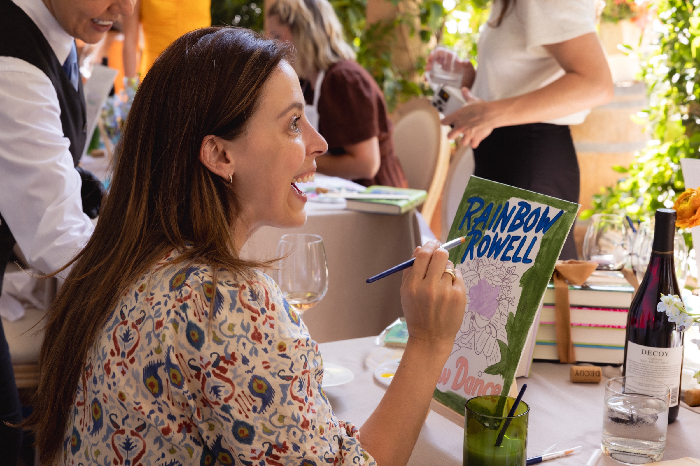 A guest painting the Slow Dance cover beside Decoy wine and flowers